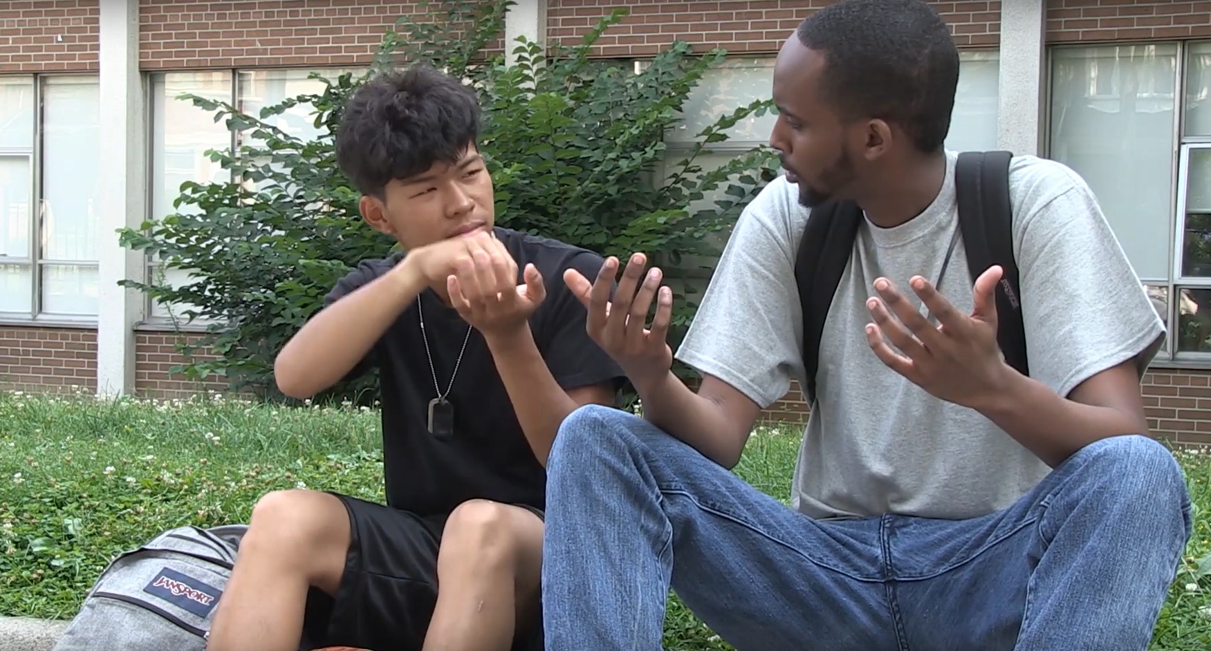 two young men sitting outside signing in conversation