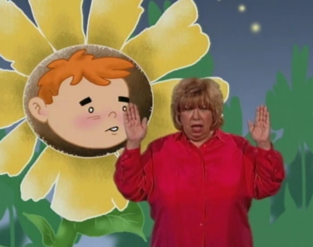 woman signing in front of a cartoon of a flower with a boy's face in the middle