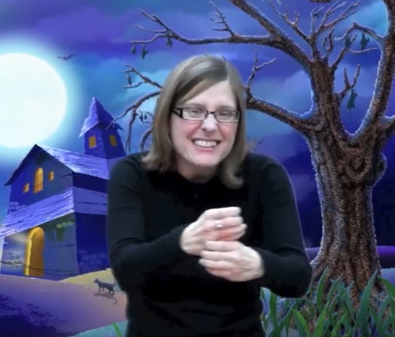 woman signing in front of a scary house and old tree at night